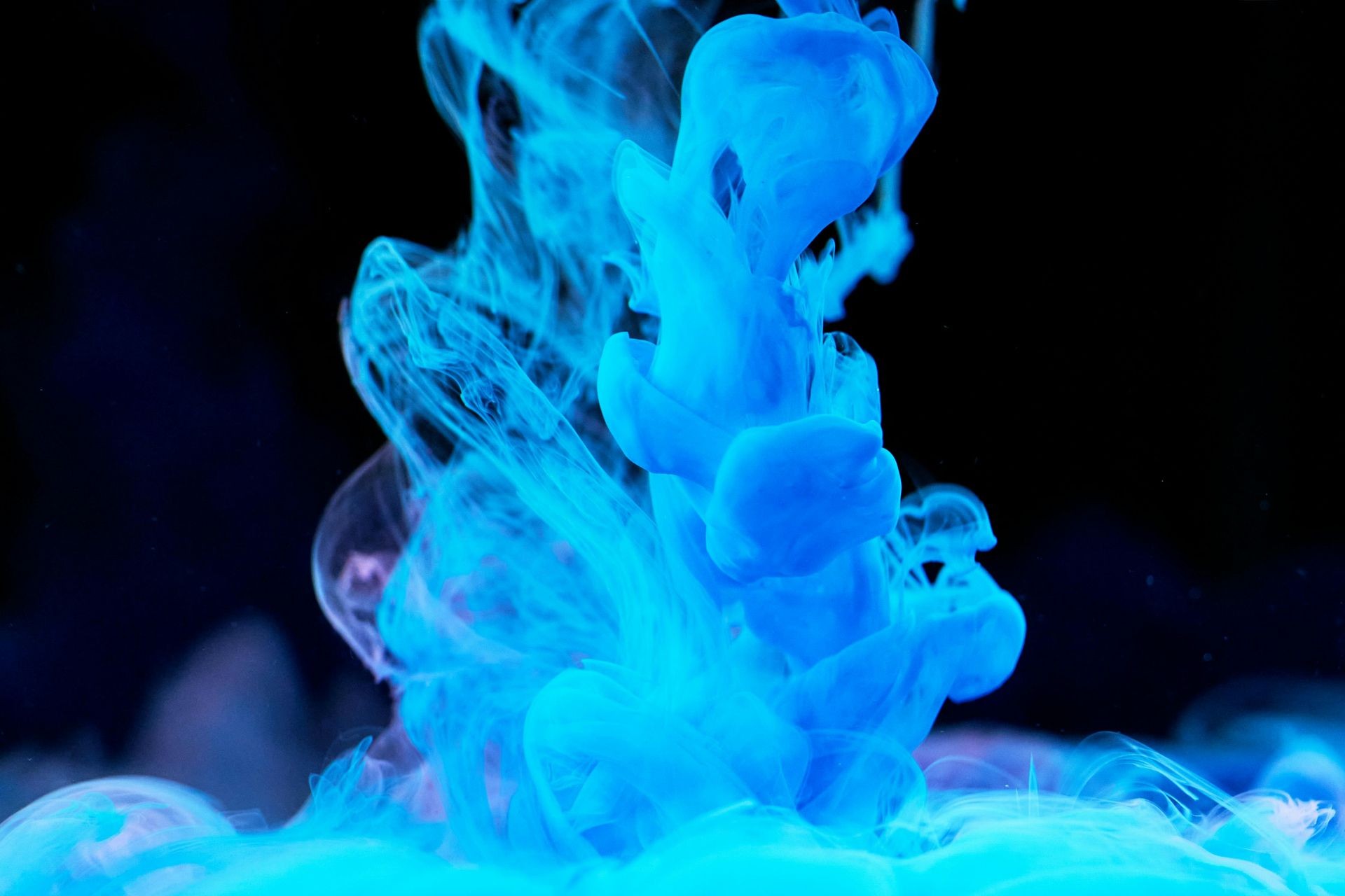 Abstract swirling blue smoke against a dark background.